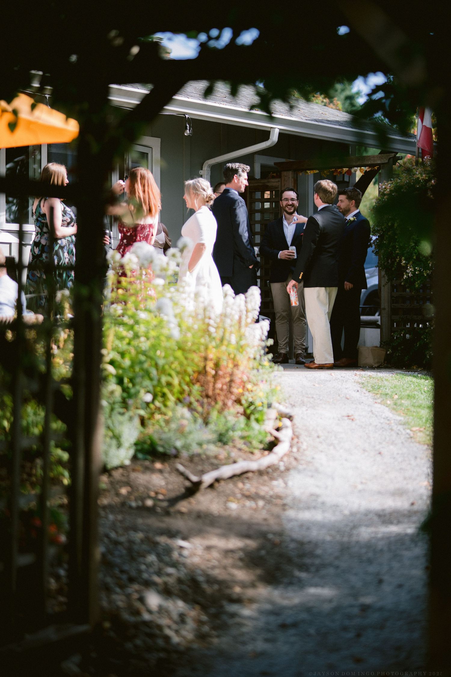 A series of candid wedding photos showing guests walking along a garden path with flowers and greenery.