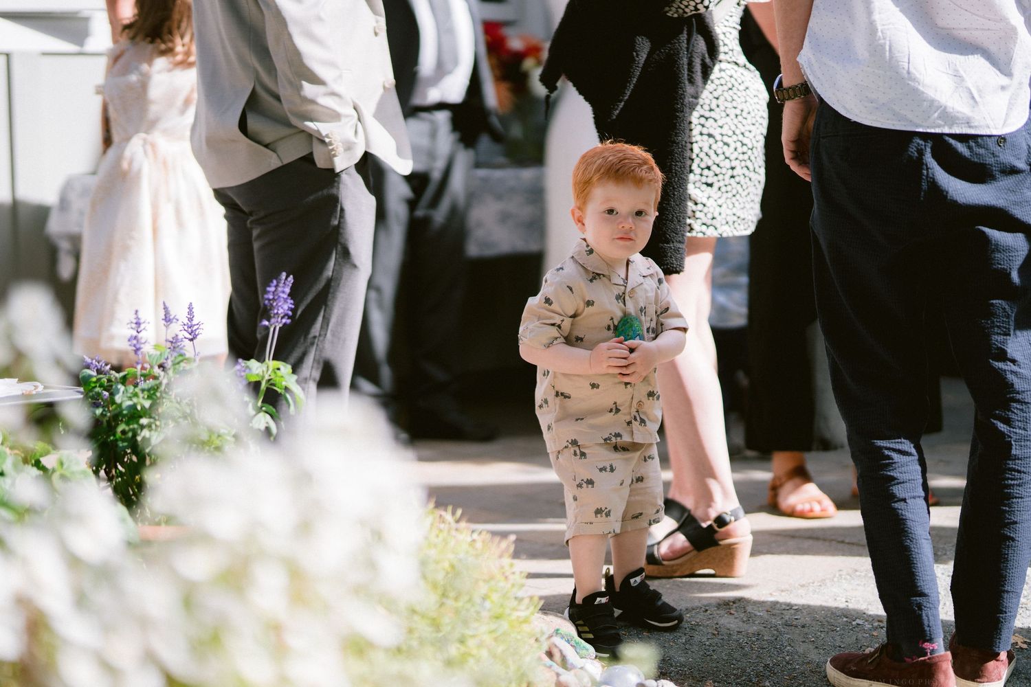 Wedding guests mingle and socialize at an outdoor reception with tables and chairs.