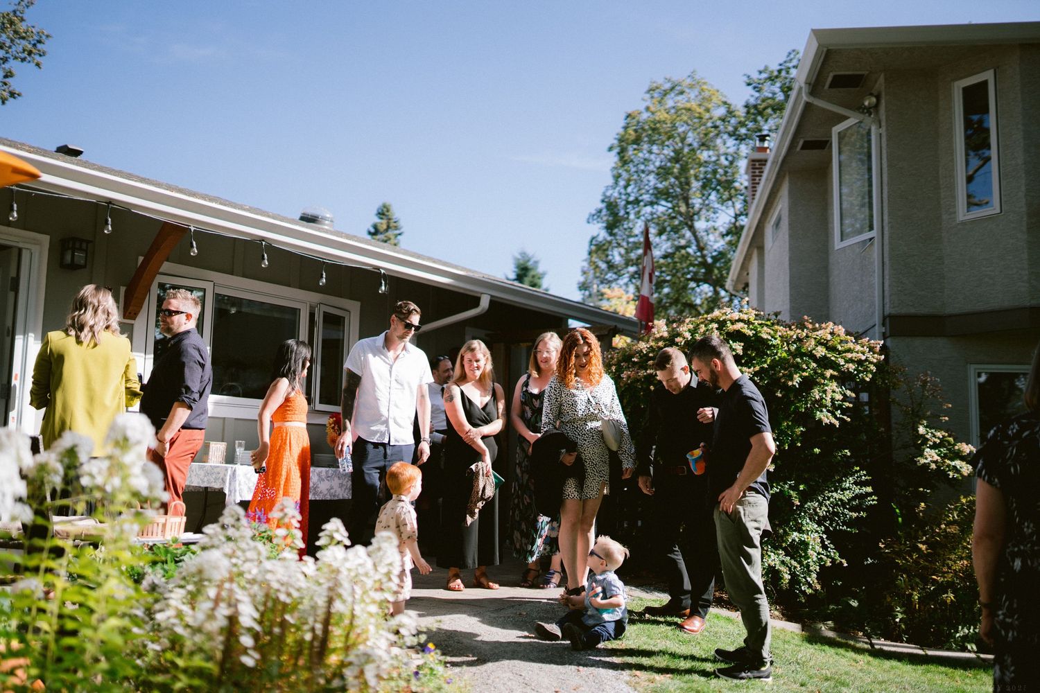 Panoramic view of wedding guests gathered outside a residential home during a celebration.