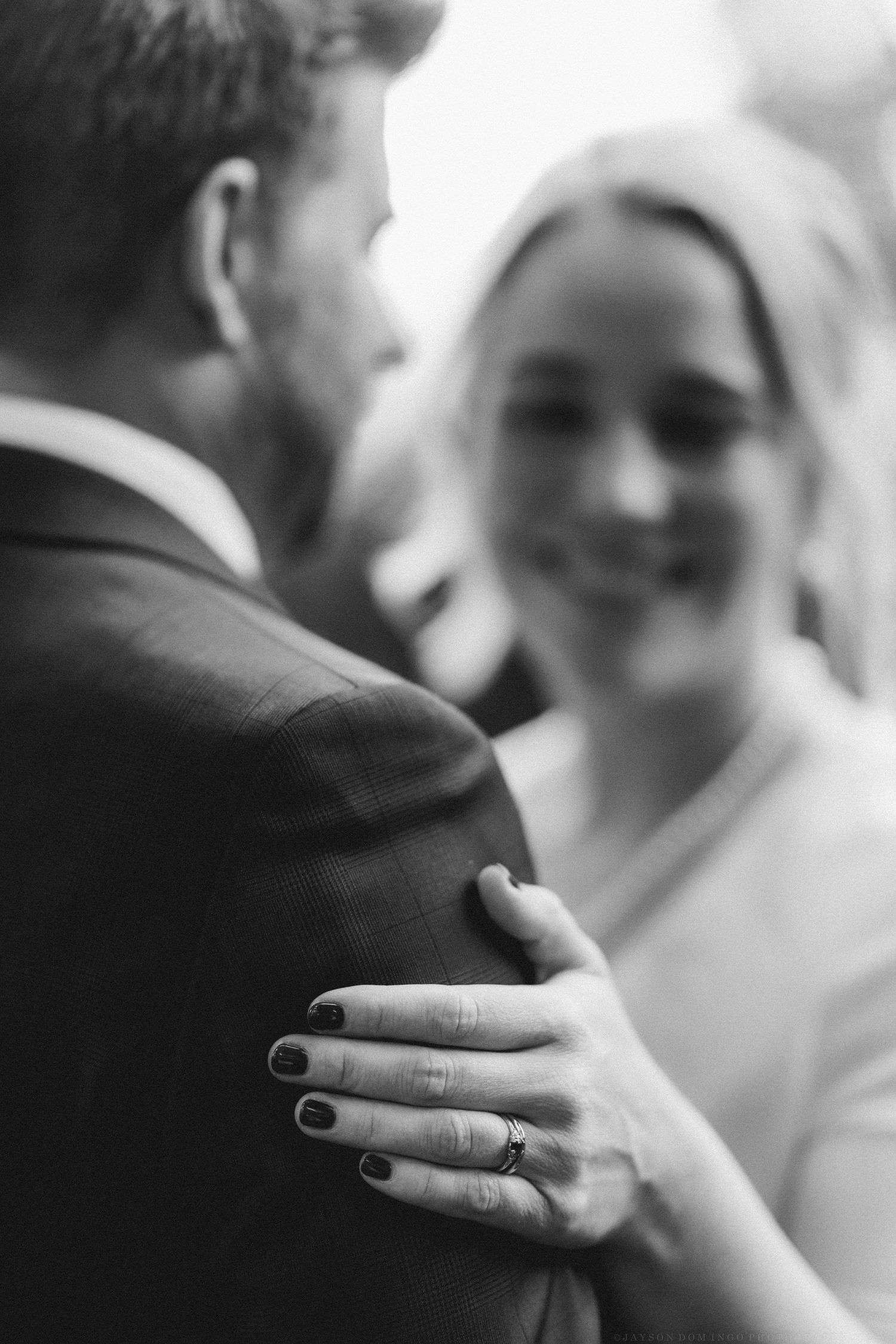 Black and white close-up of wedding rings being exchanged during the ceremony.
