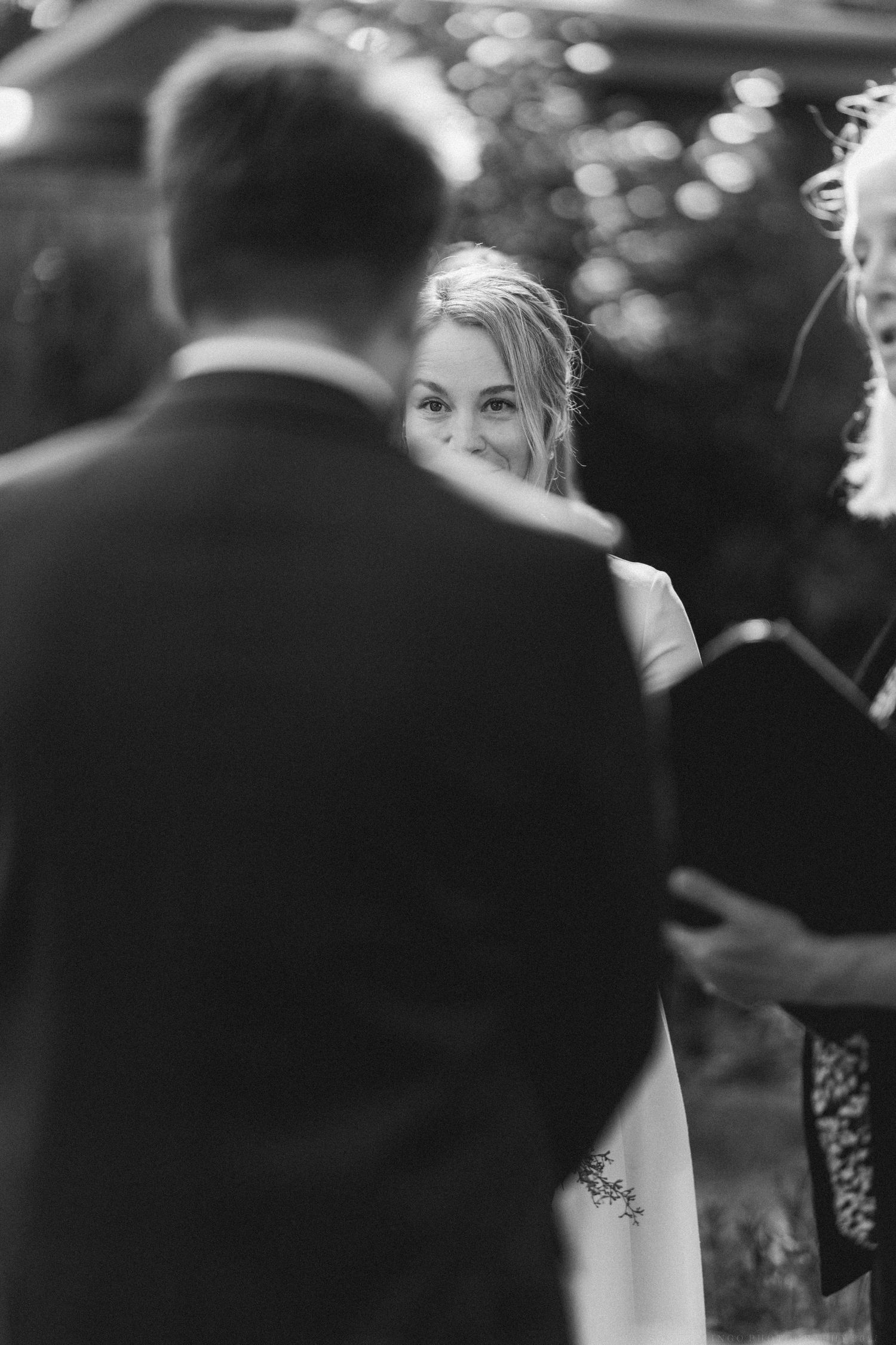 Guests mingle at an outdoor wedding reception with bokeh lighting effects in the background.