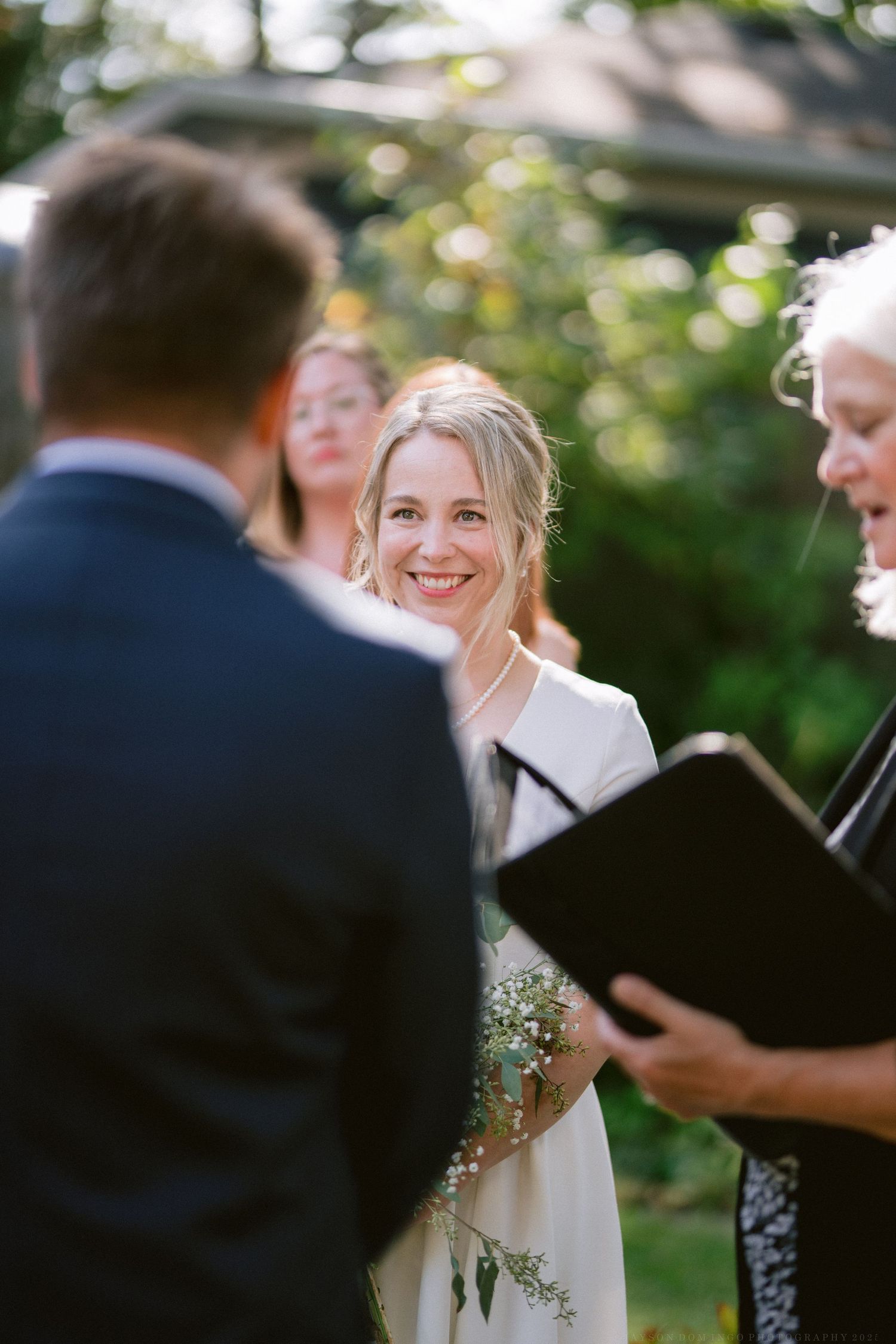 An outdoor wedding ceremony in progress with guests gathered in a garden setting.