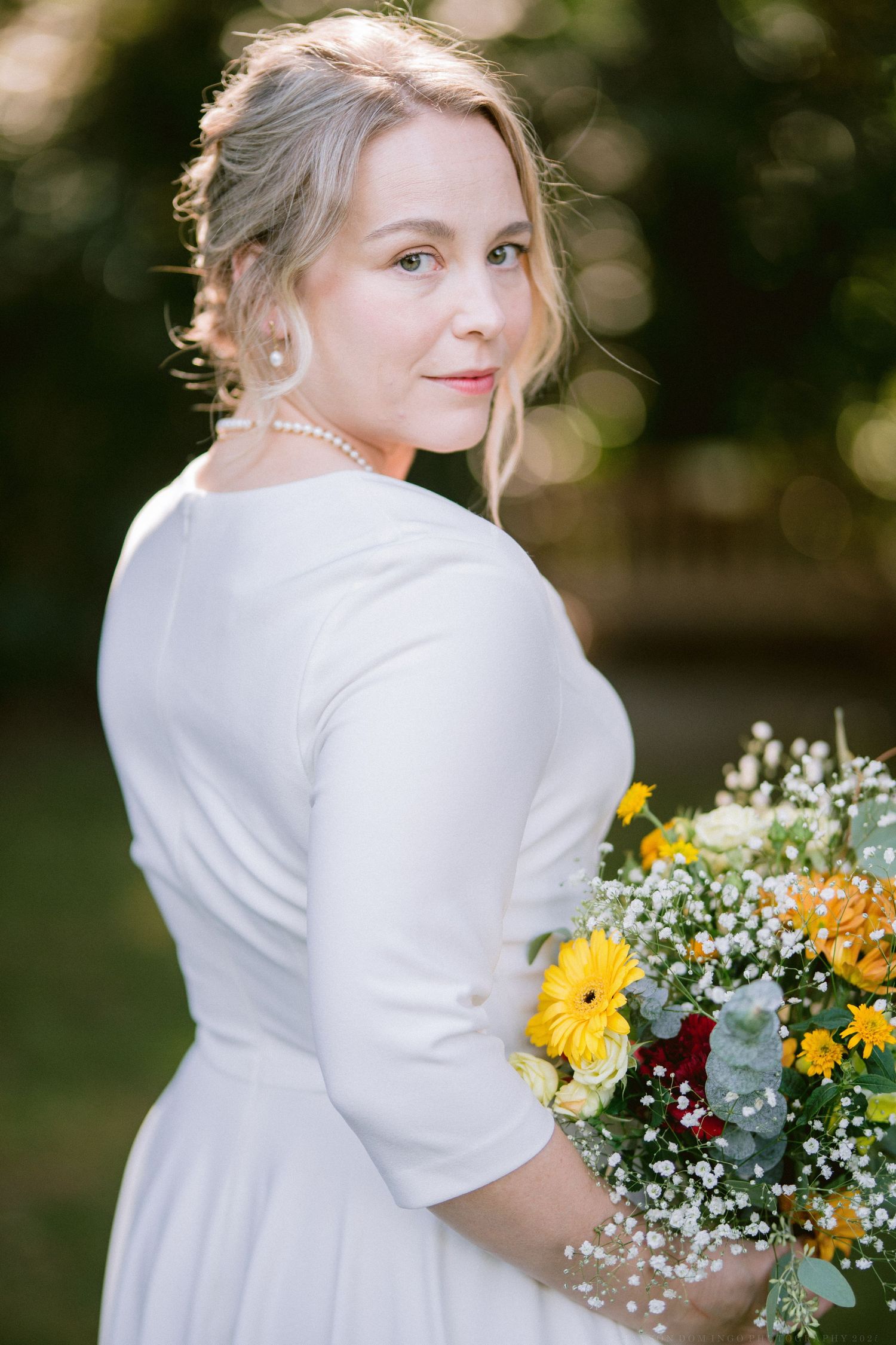 A wedding portrait series showing a bride in a white dress holding a vibrant yellow and burgundy floral bouquet.
