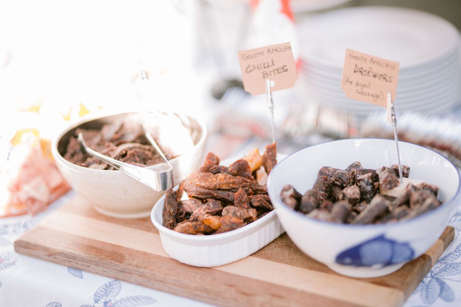 Chocolate truffles and candies arranged on white plates with small pink labels on wooden surface.