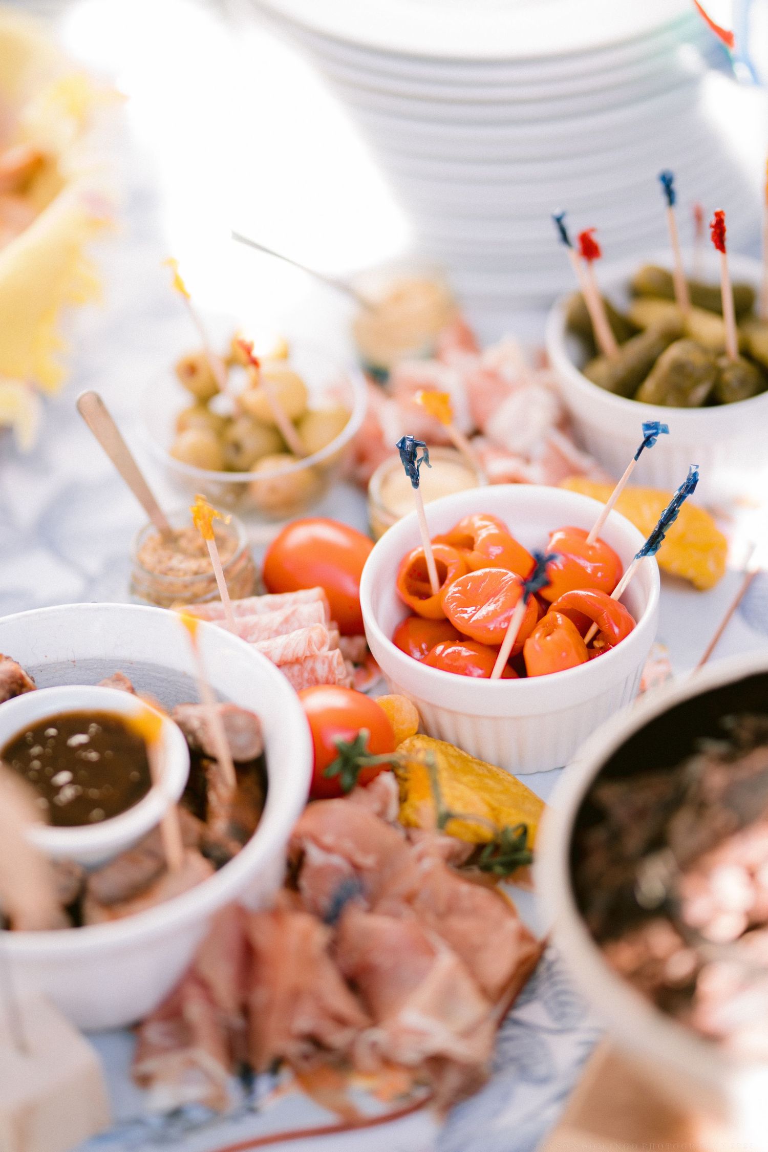 Appetizer spread featuring small bites and dips served in white ramekins with colorful garnishes.