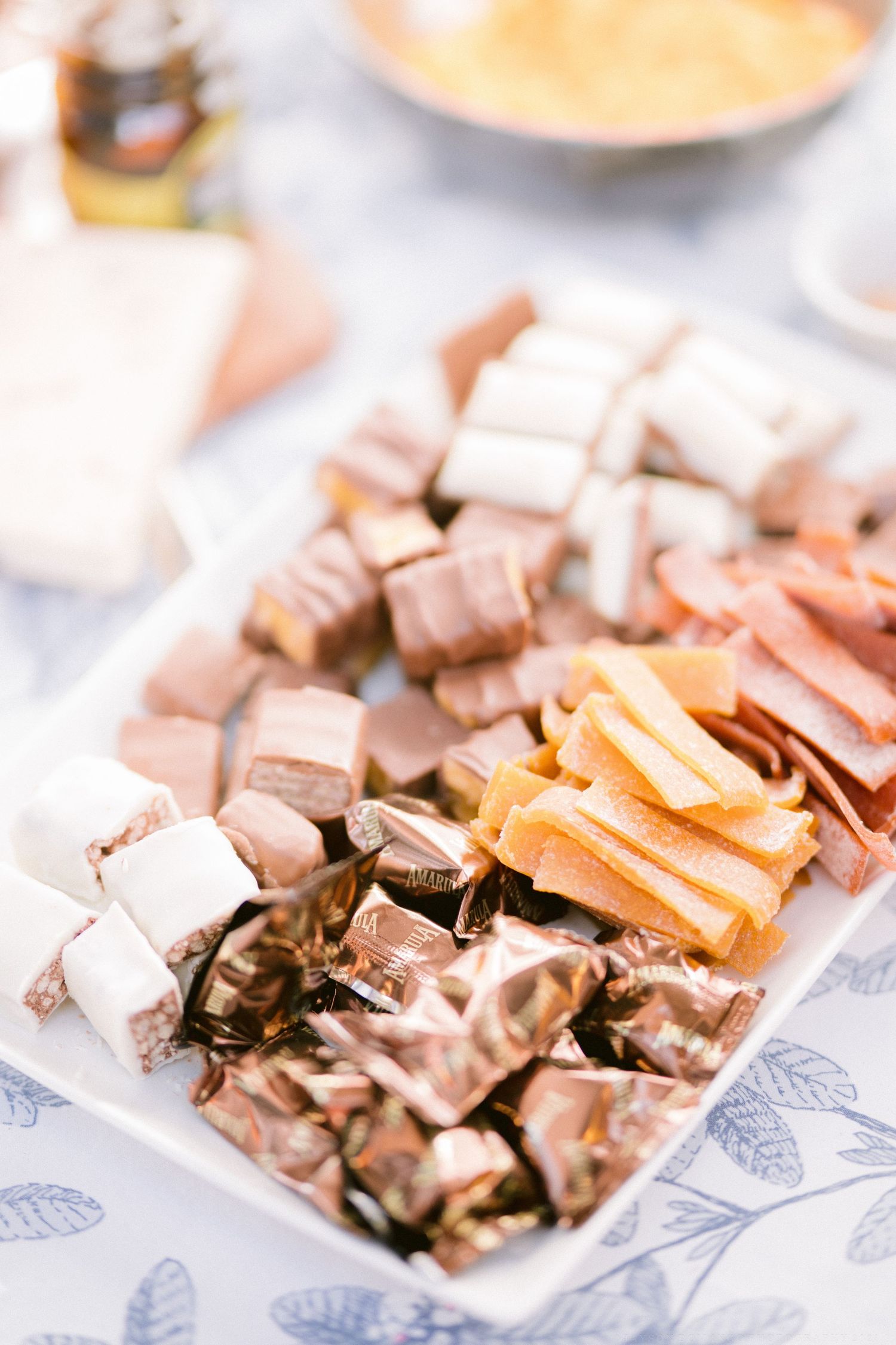 Chocolate candies and caramel pieces arranged on decorative blue and white plates for a wedding dessert table.
