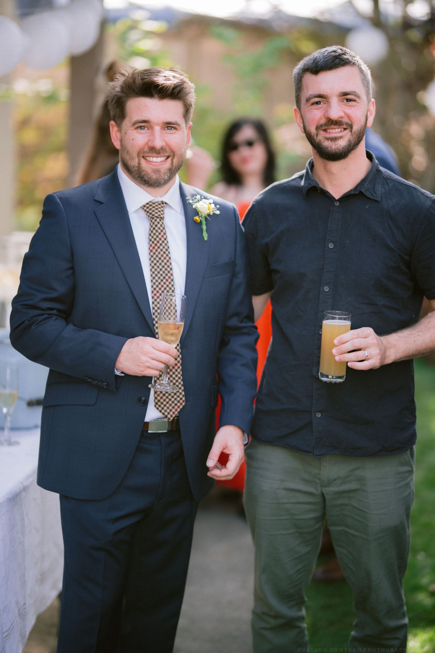 Groomsmen in suits share drinks and laughs during wedding festivities.