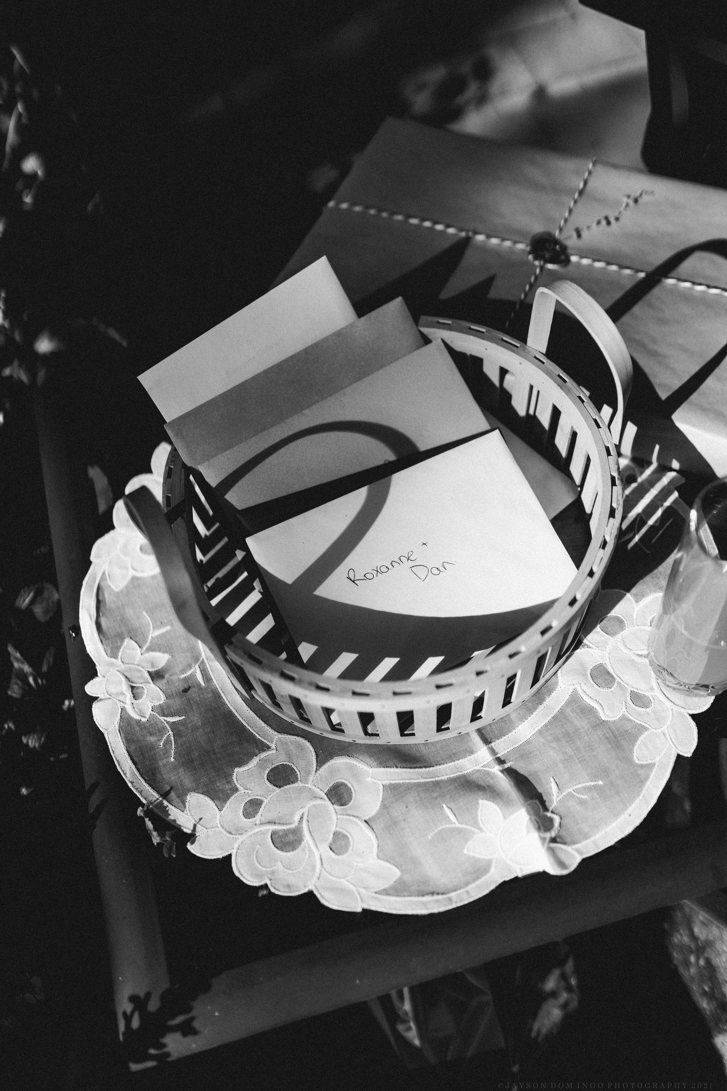 Black and white detail shot of decorative white lace and ribbon elements at a wedding.