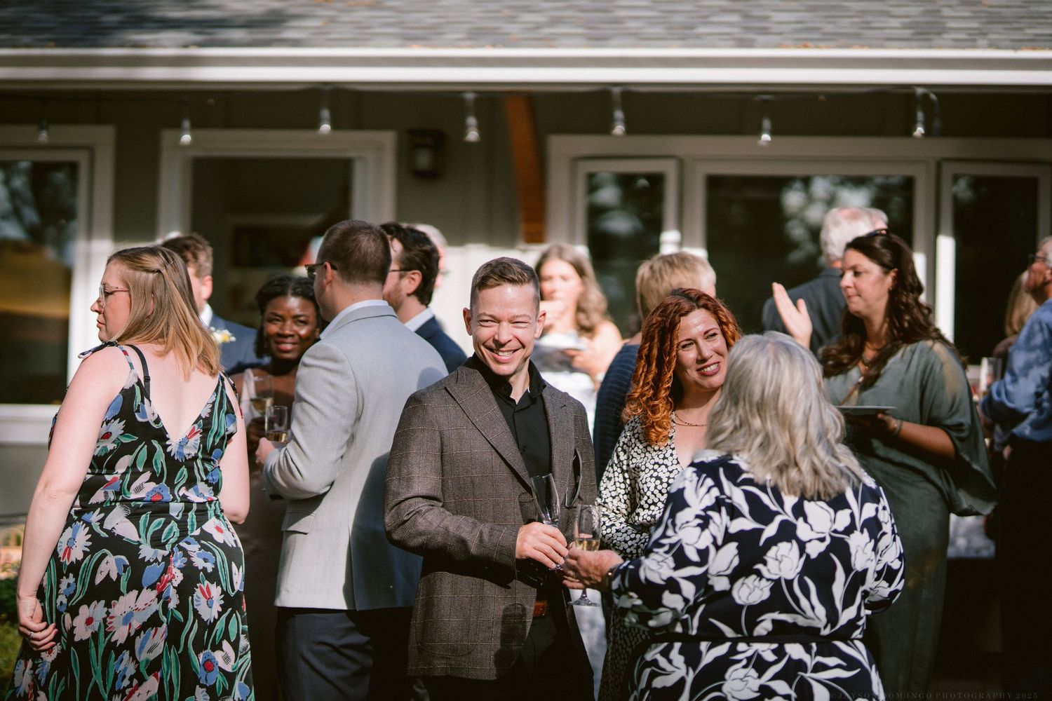 Wedding guests enjoy a candid moment together during an outdoor celebration at a rustic venue.