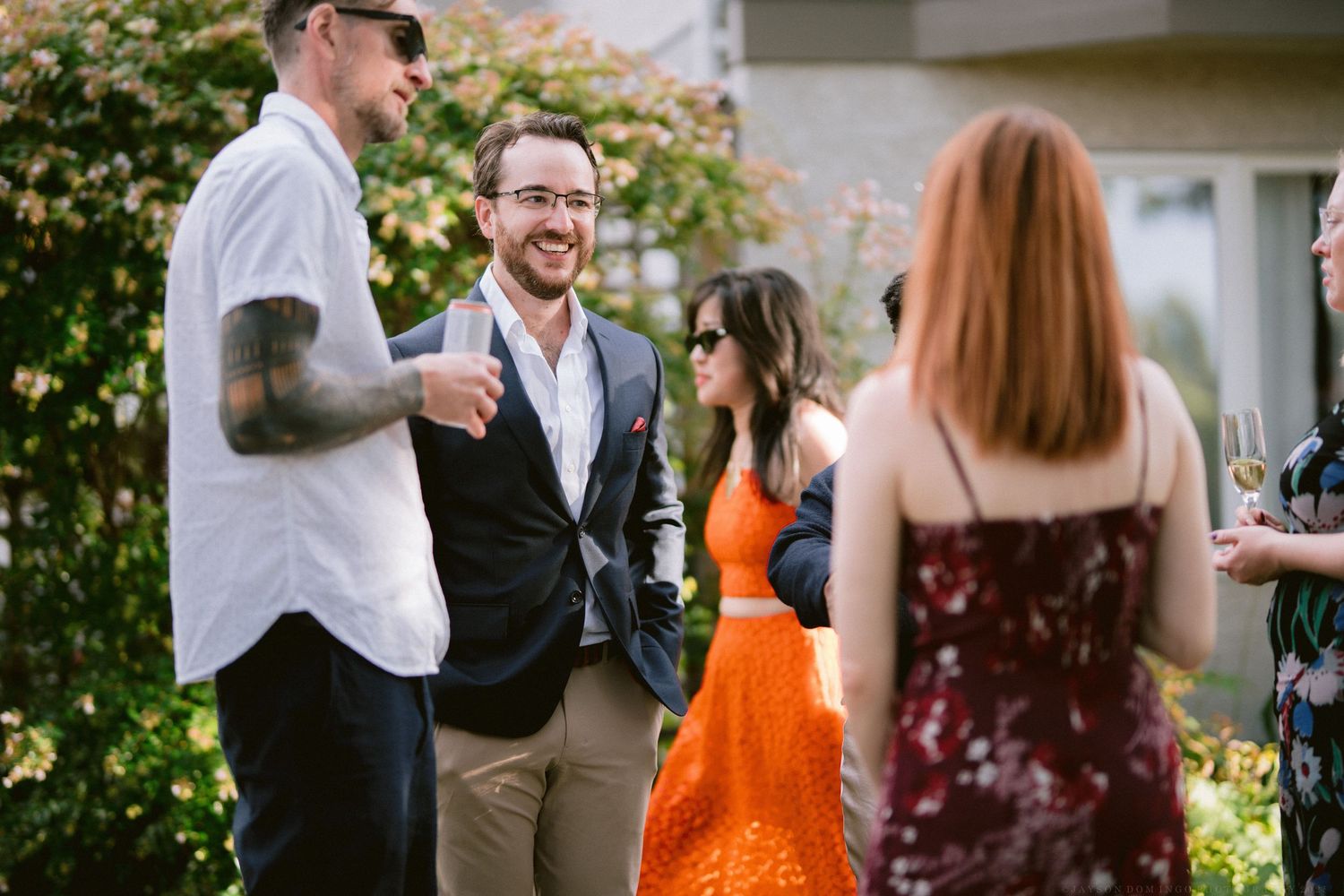 A group of friends enjoying conversation and laughter at an outdoor social gathering in a backyard setting.