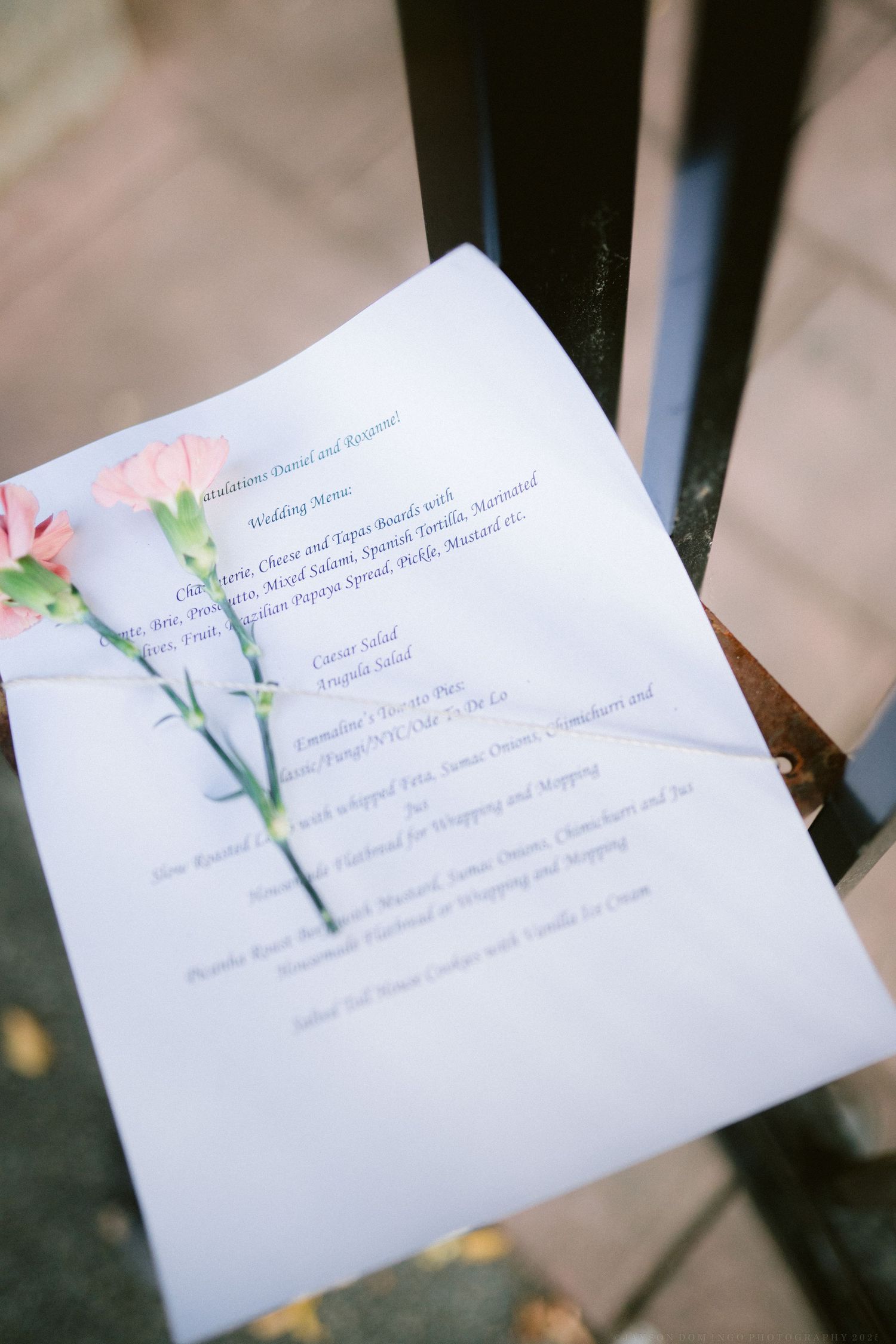 Wedding program cards decorated with delicate watercolor floral designs laid out on a dark surface.