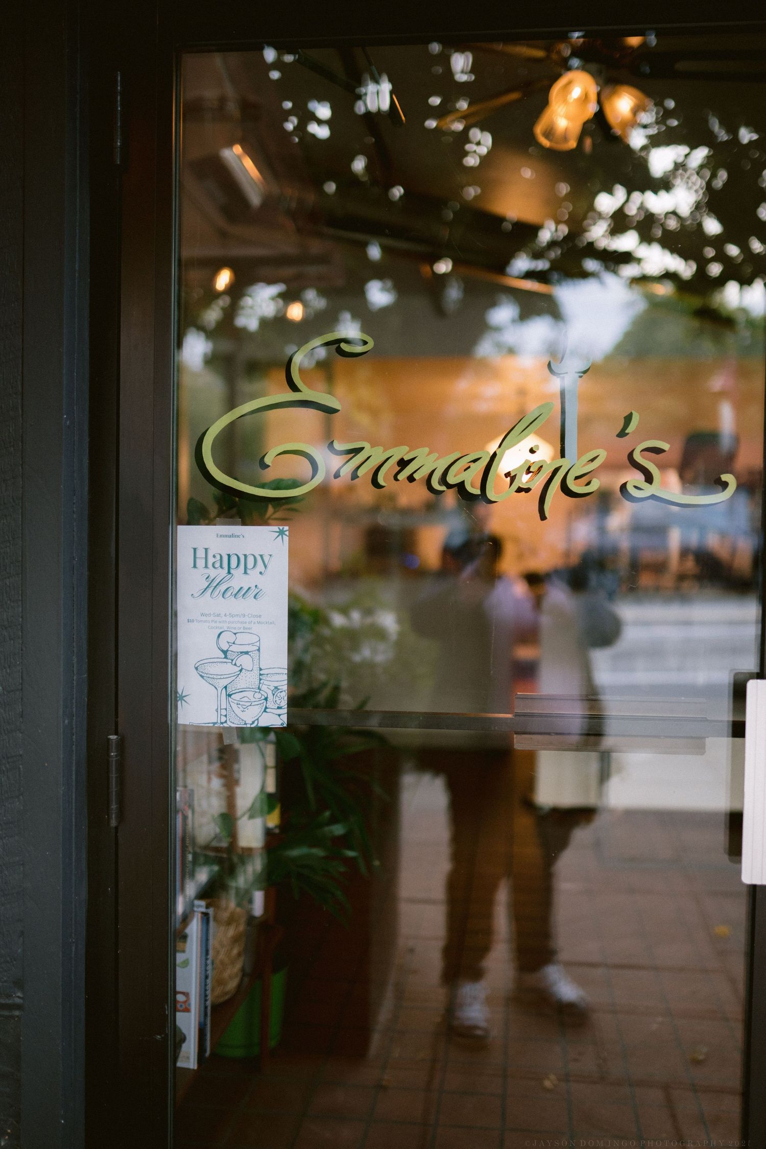 Storefront window with illuminated signage and reflections at dusk.