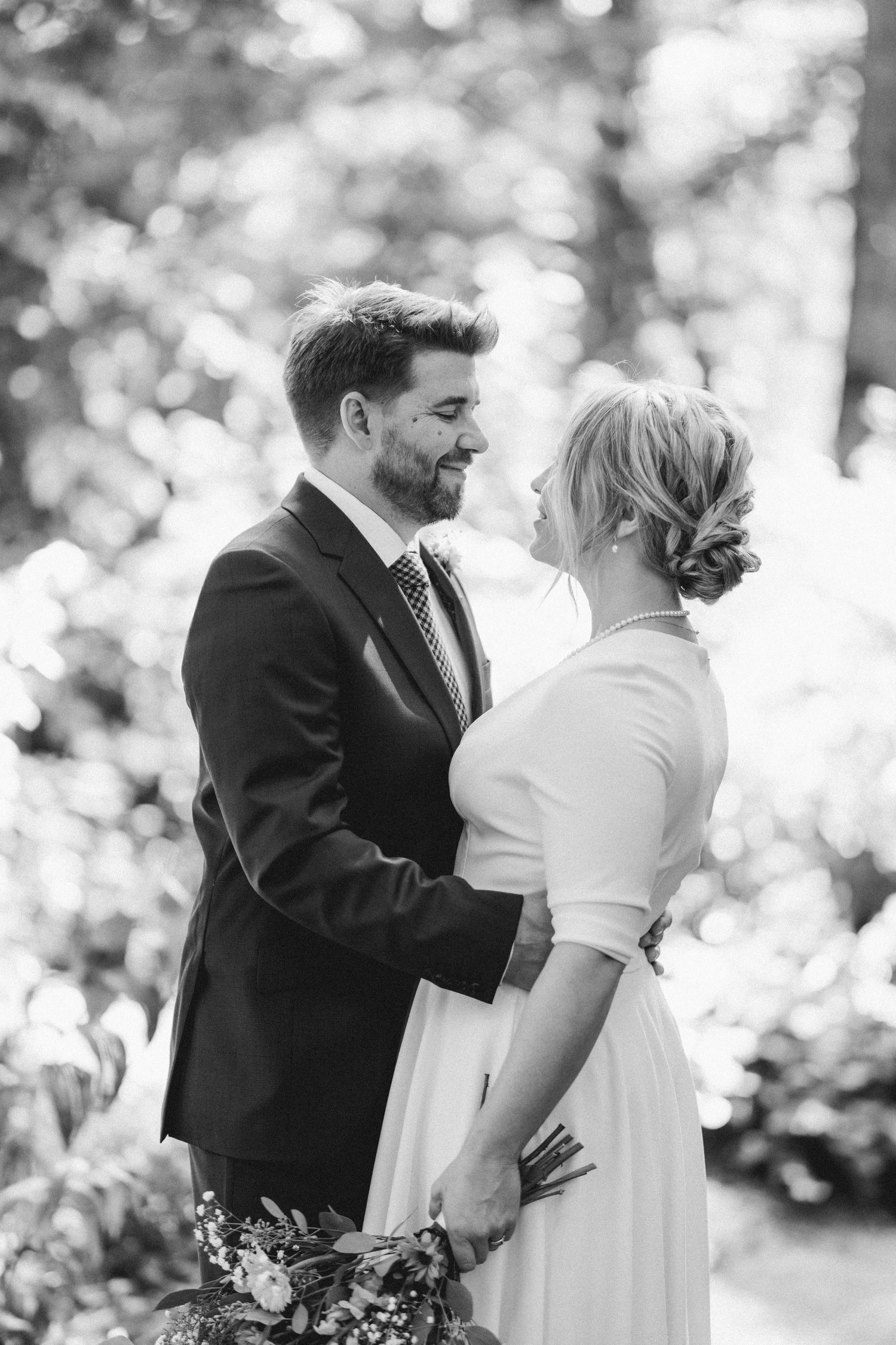 Black and white portrait of newlyweds sharing an intimate moment outdoors.