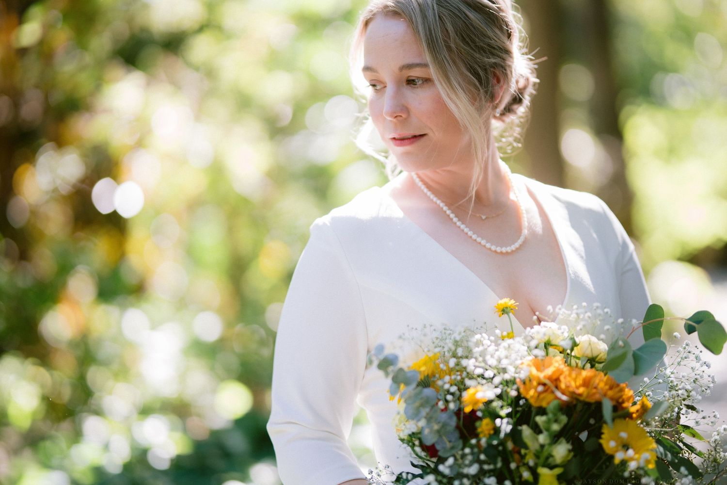Bride holding a beautiful bouquet with yellow flowers and delicate baby's breath.