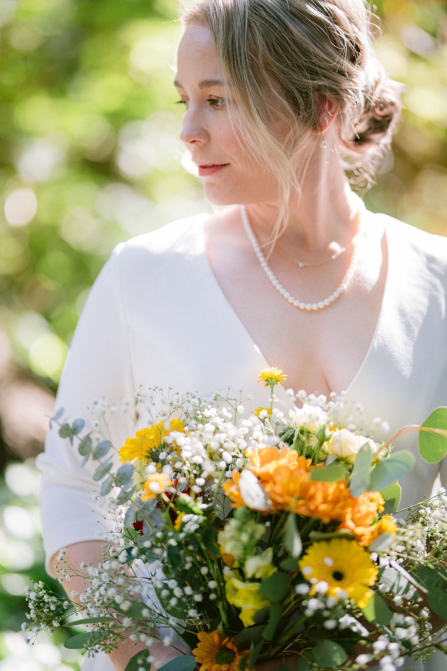Close up view of a wedding bouquet with bright yellow gerbera daisies and mixed flowers against a blurred background.