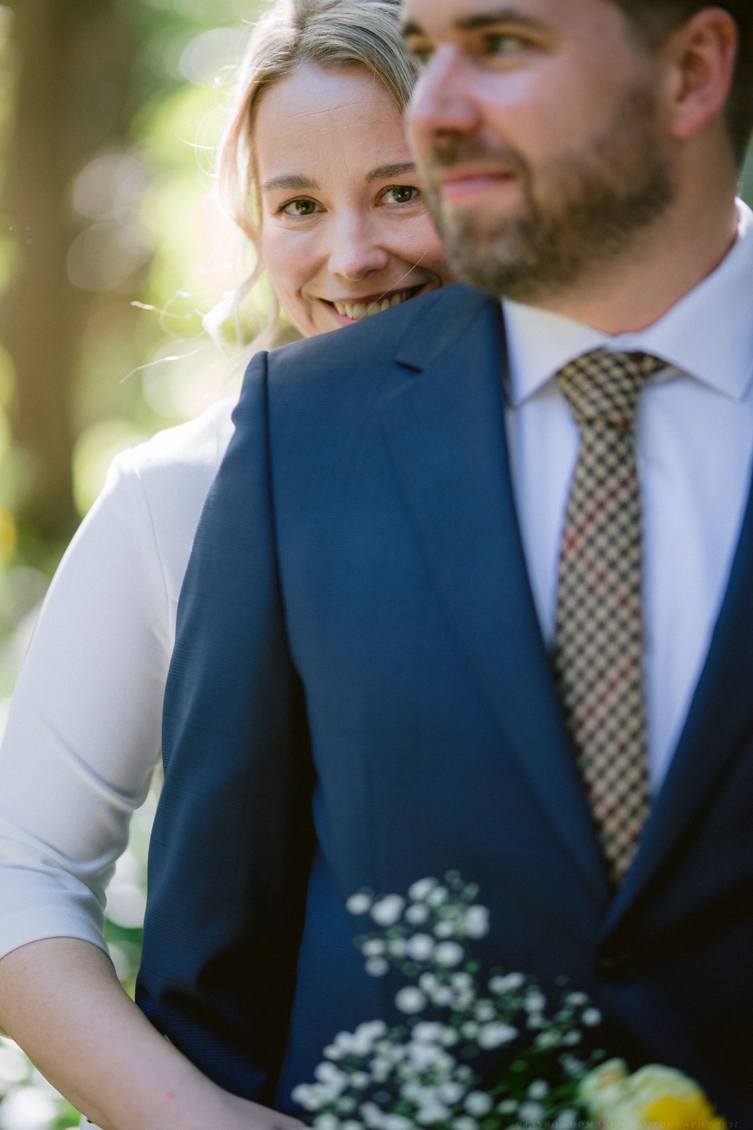 Wedding couple in navy suit and white dress photographed in natural sunlight.
