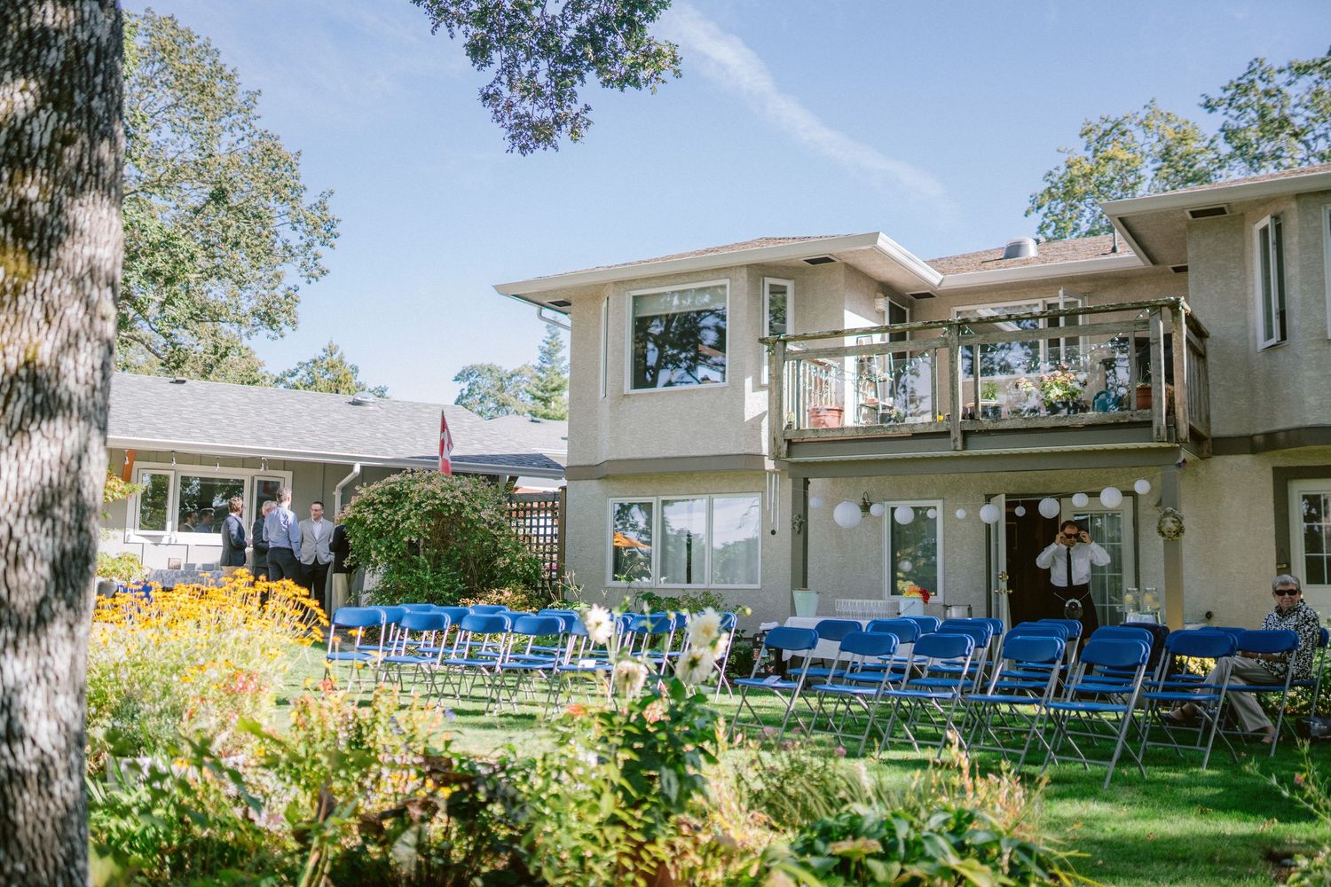 Modern white house exterior with blue chairs and landscaped garden visible.