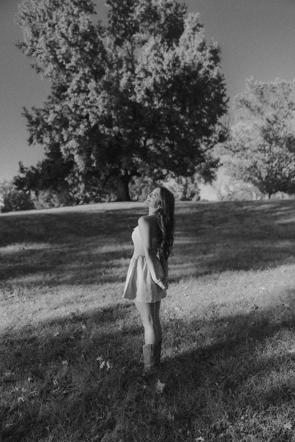 A sequence of black and white photos showing a person walking up a grassy hillside beneath trees.