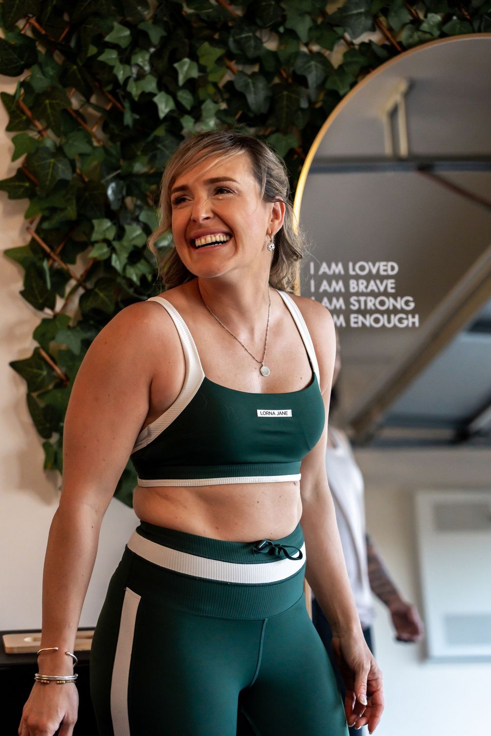 Person in teal workout attire exercising in front of motivational wall text.