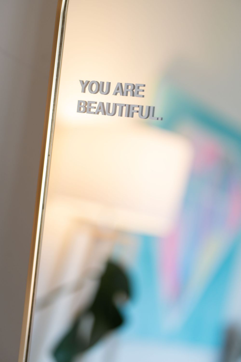 Blurred motivational text reading 'YOU ARE BEAUTIFUL' on a soft pastel background.