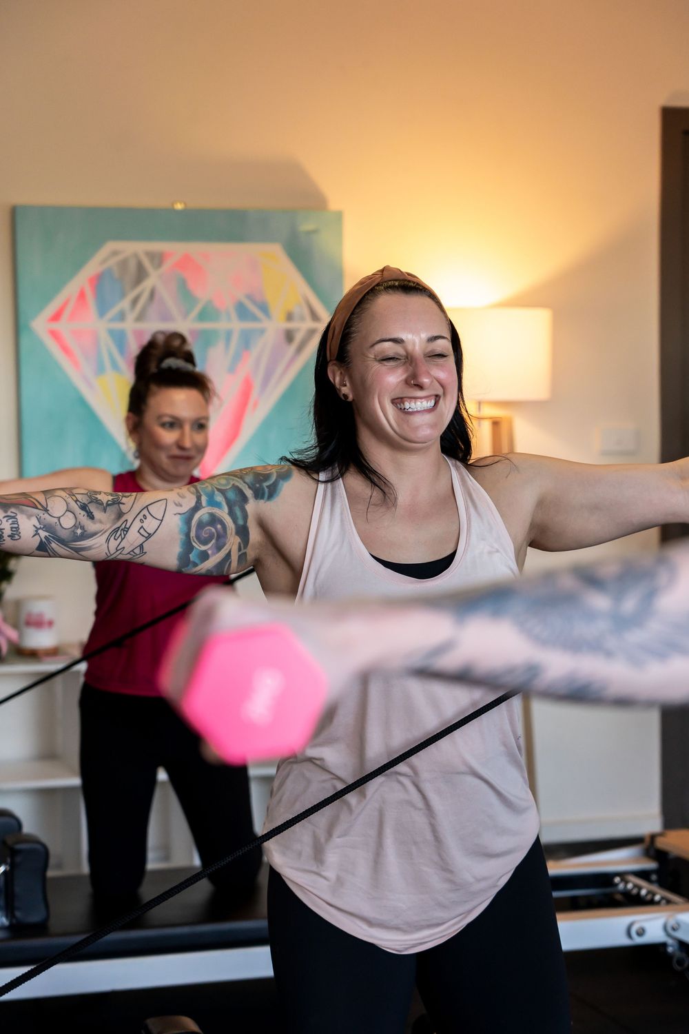People doing fitness exercises with resistance bands in a bright room with colorful wall art.