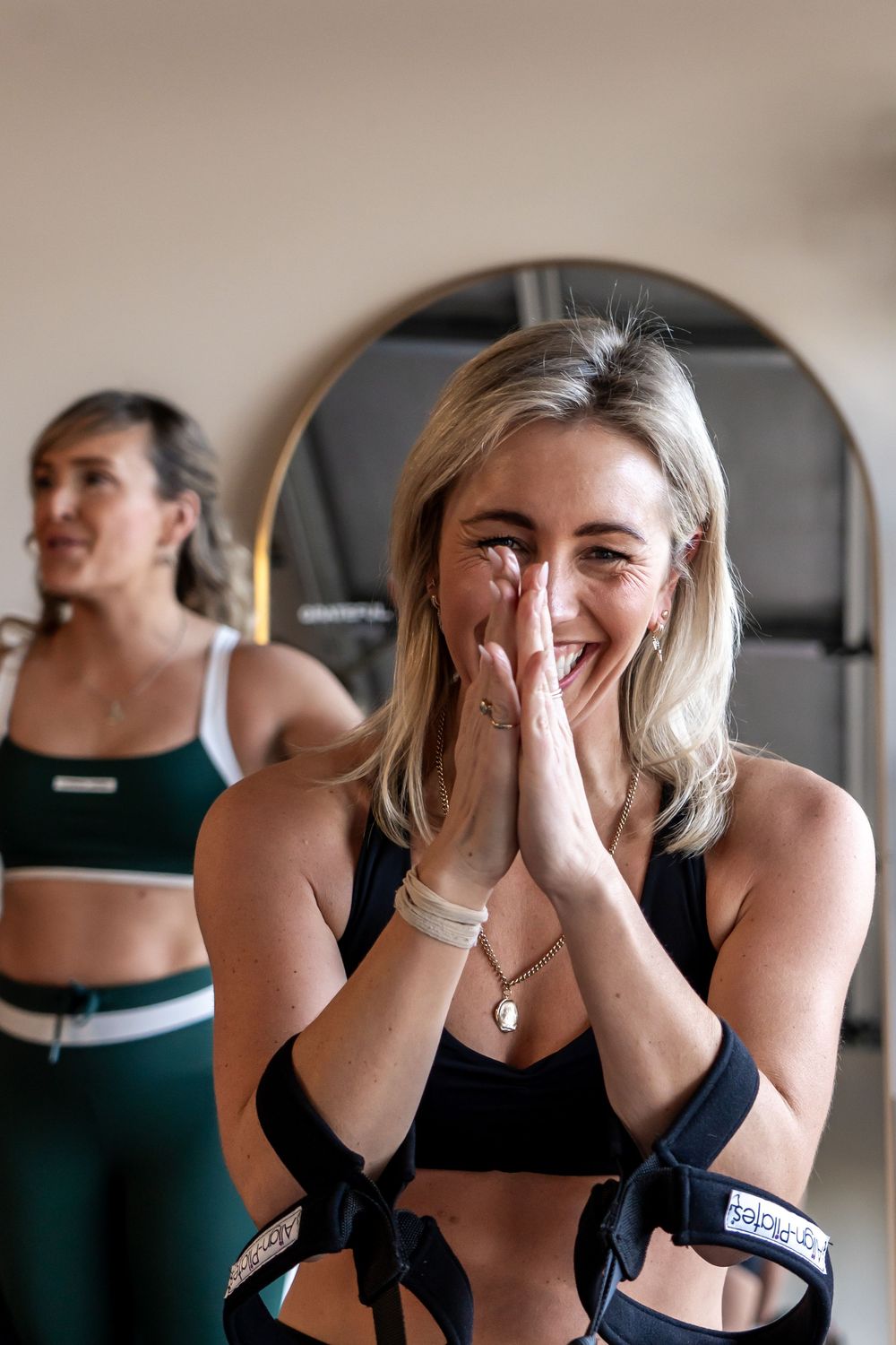 Group fitness class participants sharing laughs during a workout session in a studio setting.