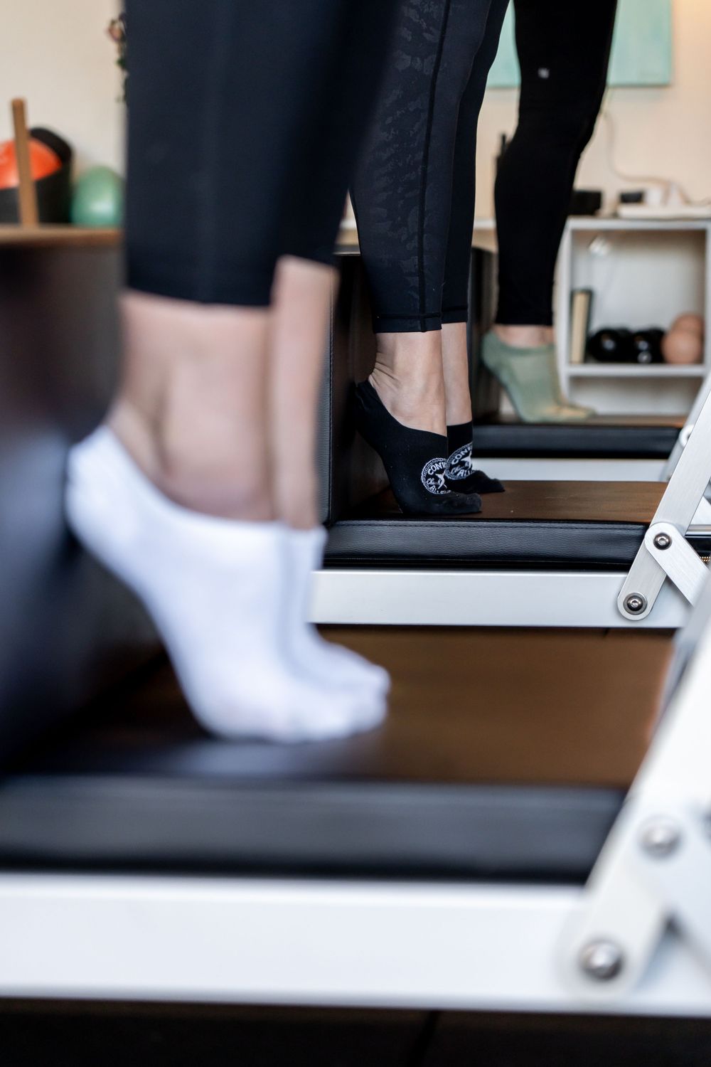 White sneakers and black leggings visible on exercise equipment in a gym setting.