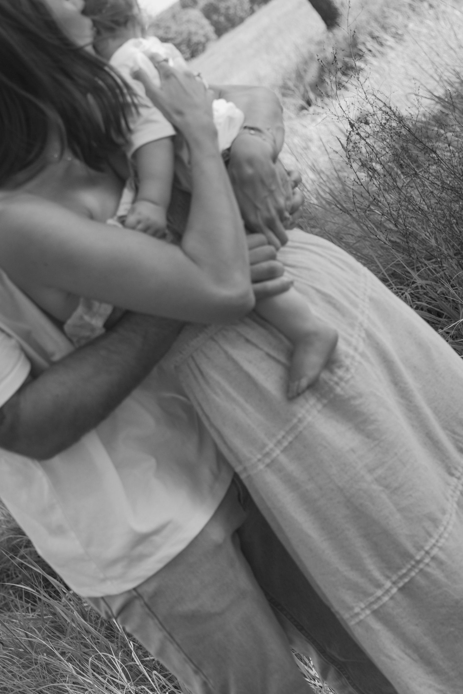 Maternity photoshoot setup with baby clothes on clothesline and vintage suitcase on blanket.