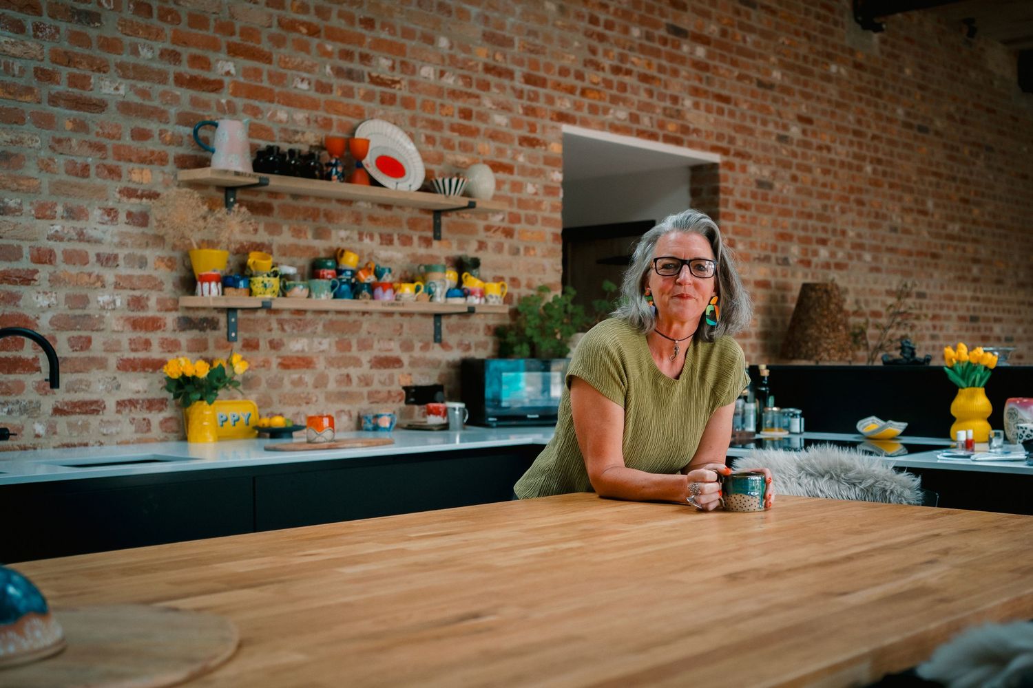 Wooden table surface in a workshop with exposed brick walls and workshop tools visible in the background.