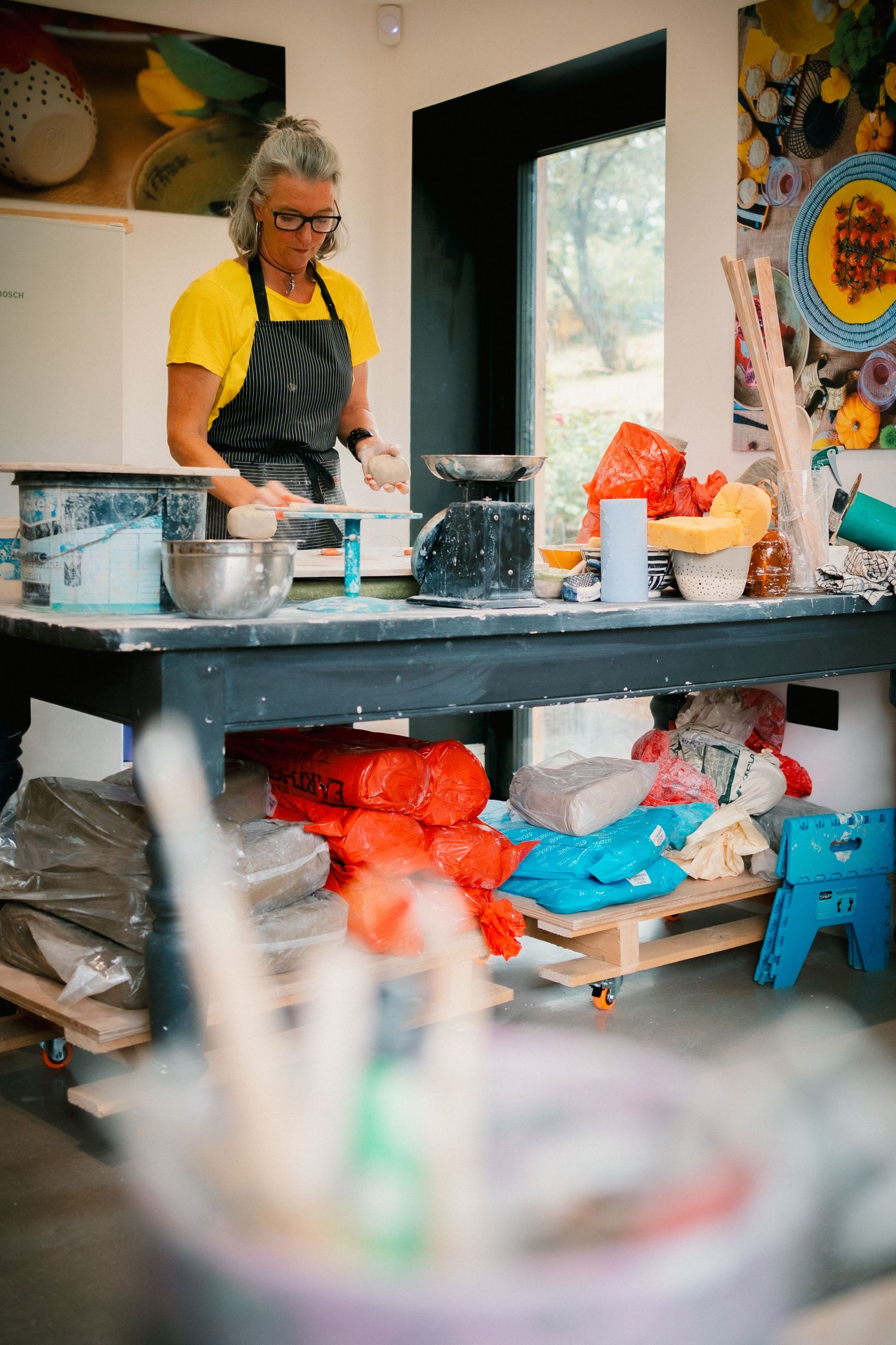 Hands working at a pottery studio table with colorful clay and various tools visible in a series of connected shots.