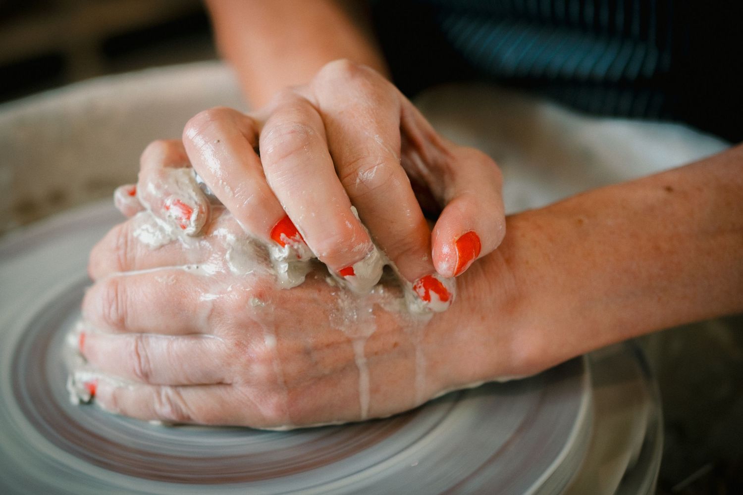 Hands kneading and shaping raw dough on a white surface during bread making preparation.