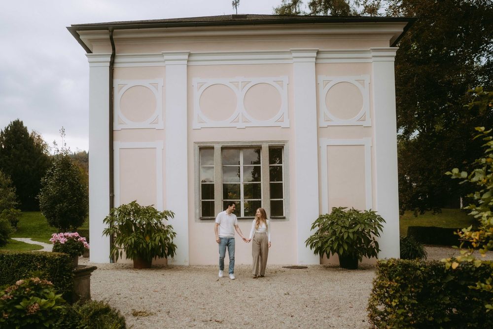 White architectural facade with traditional windows and potted plants on a gravel path.