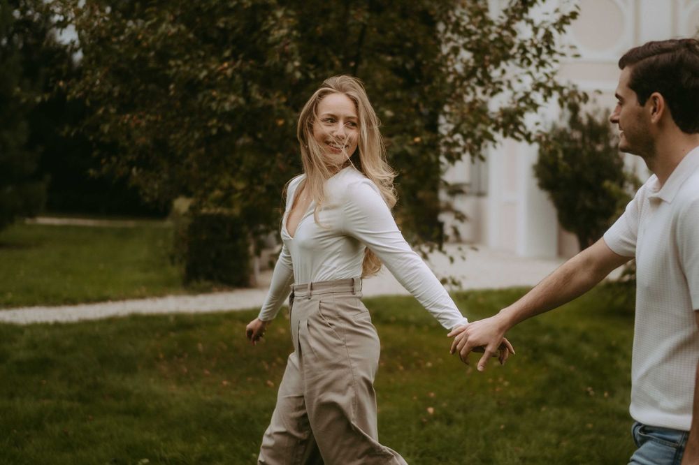 Playful couple interaction captured in natural outdoor setting with trees in background.
