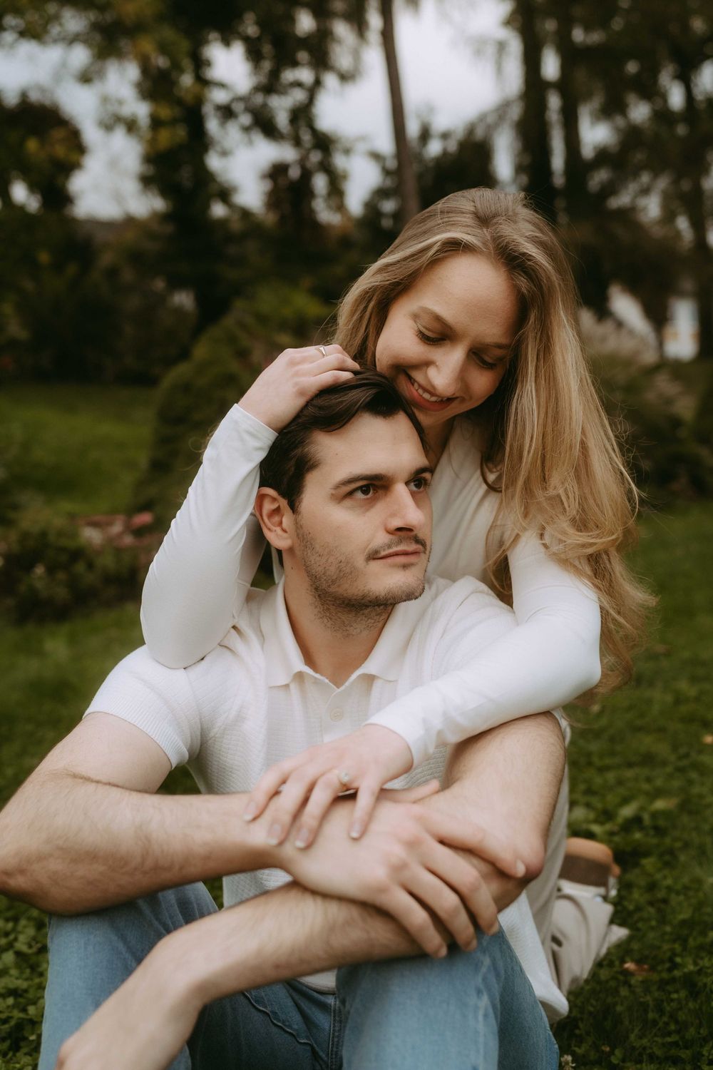 Couple sharing affectionate moments while sitting together on green grass.