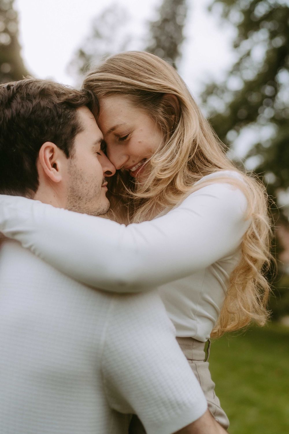 Close-up shots of couple in white sweaters sharing intimate moments outdoors.
