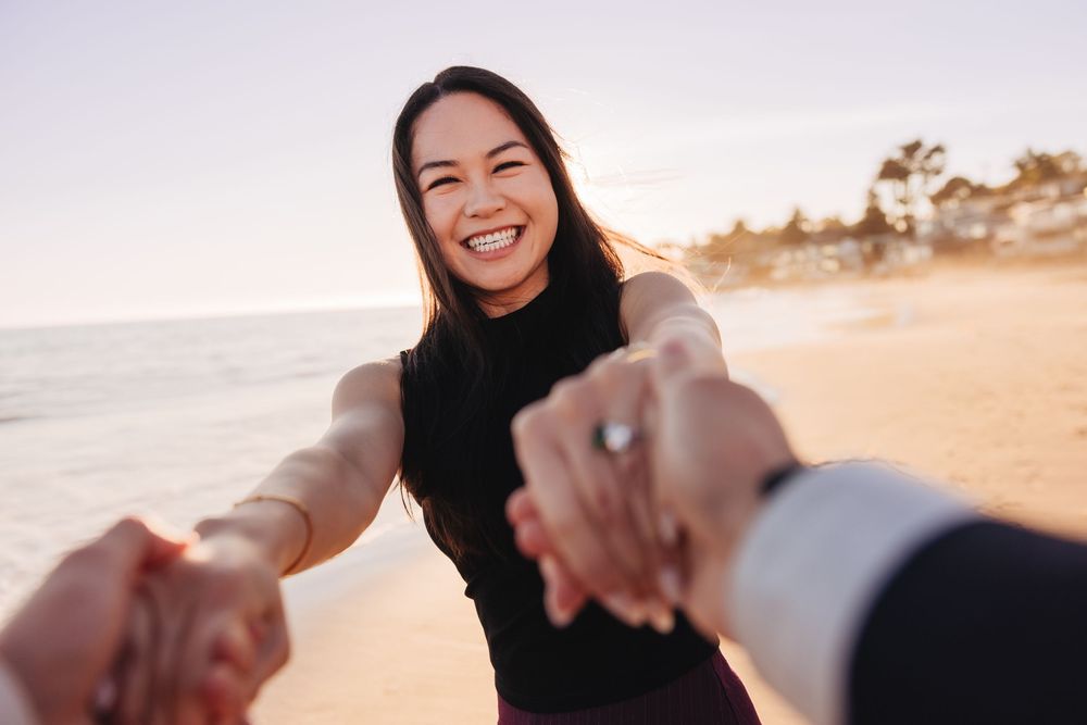 A couple shares a joyful moment together on a sandy beach at sunset.