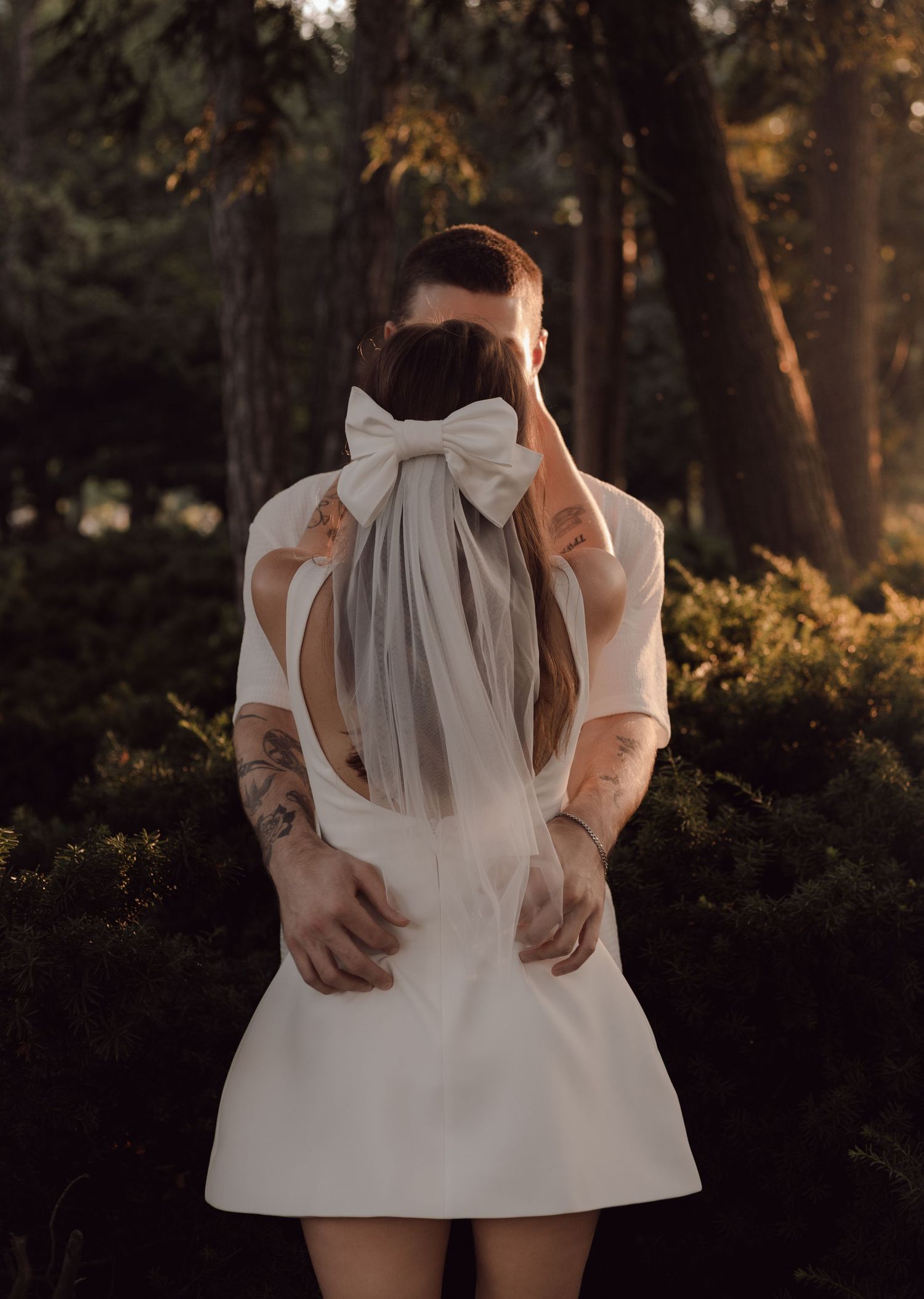 Beautiful shot of bride and groom slow dancing in the sunlight. Her short white veil is captured.
