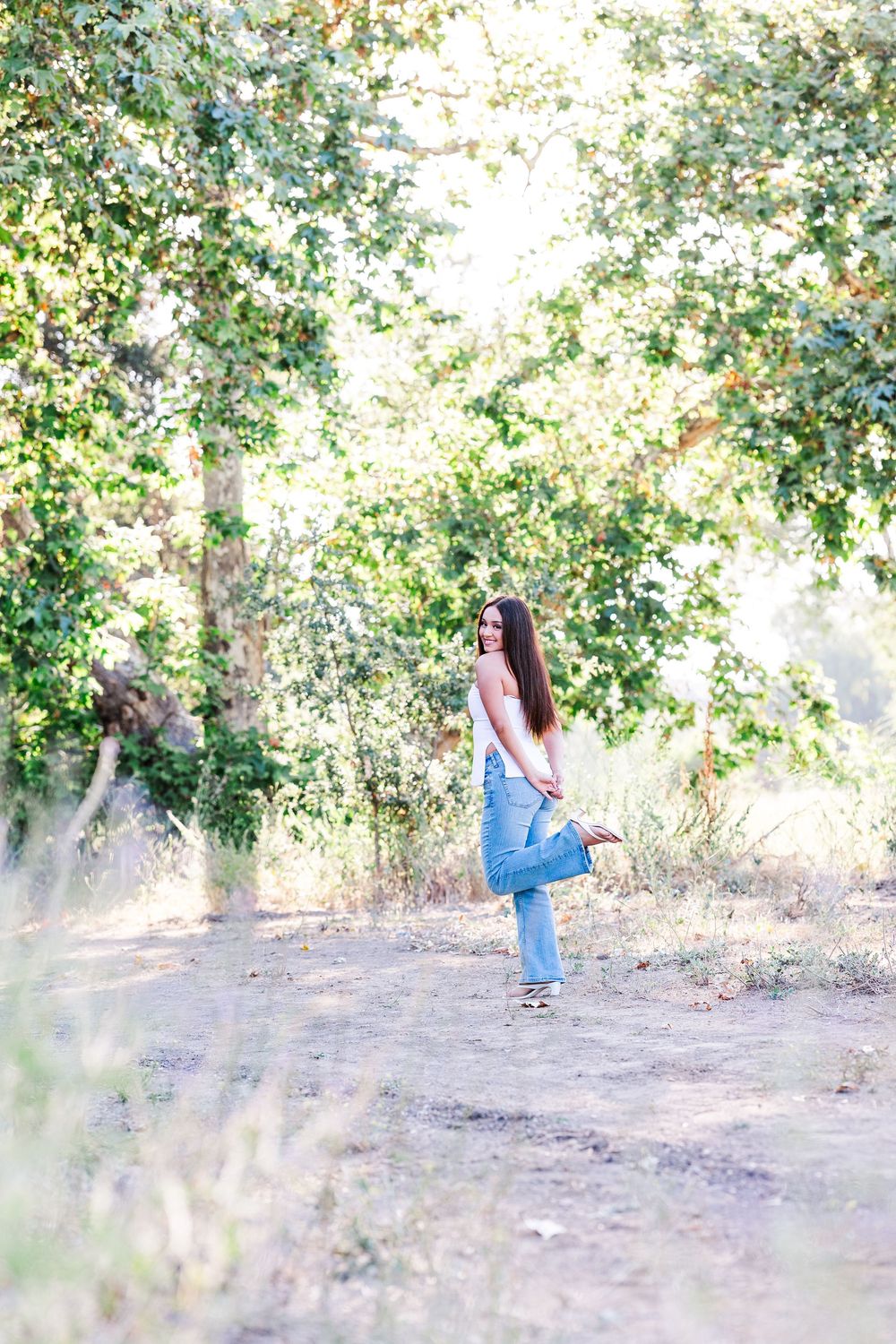 Simi Valley photographer captures Ashlyn in a playful outdoor portrait session at Challenger Park with trees and riverbed backdrops.