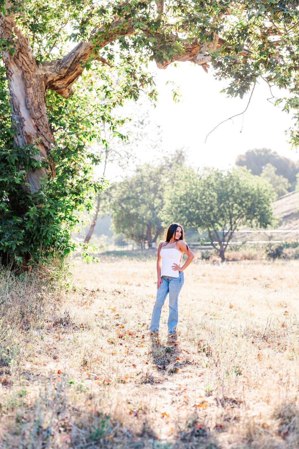 Simi Valley photographer captures Ashlyn in a playful outdoor portrait session at Challenger Park with trees and riverbed backdrops.