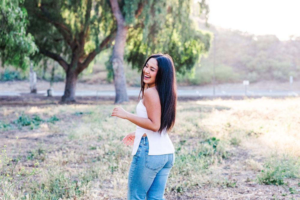 Simi Valley photographer captures Ashlyn in a playful outdoor portrait session at Challenger Park with trees and riverbed backdrops.