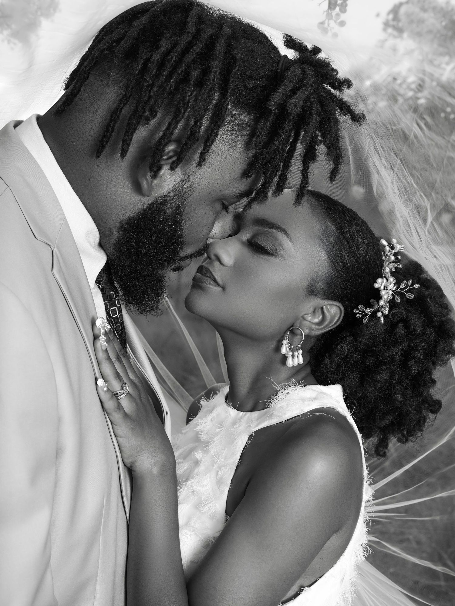 A tender black and white portrait of a romantic couple sharing an intimate moment in wedding attire.