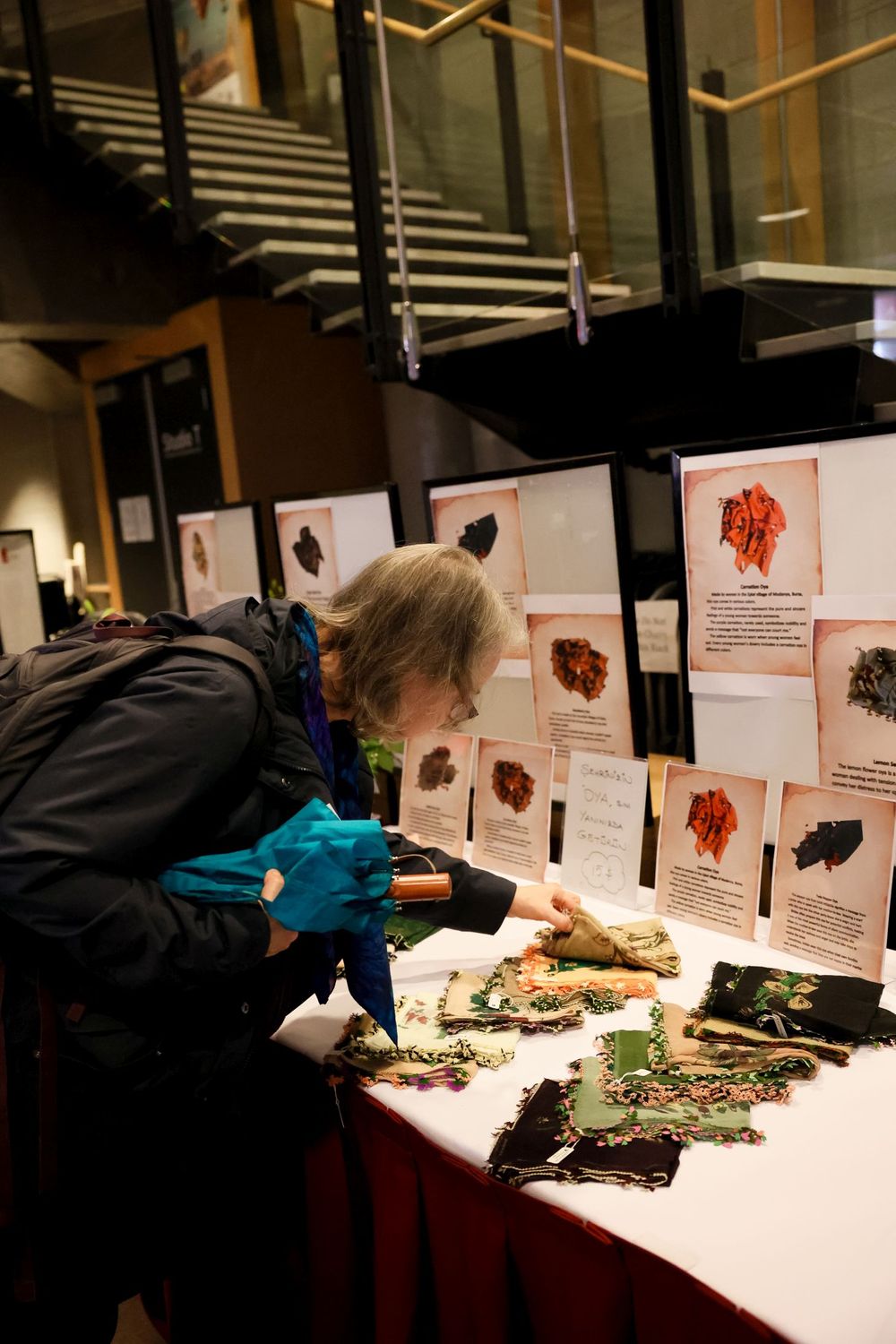 Someone examines a display of natural specimens and scientific illustrations laid out on a red-covered table.