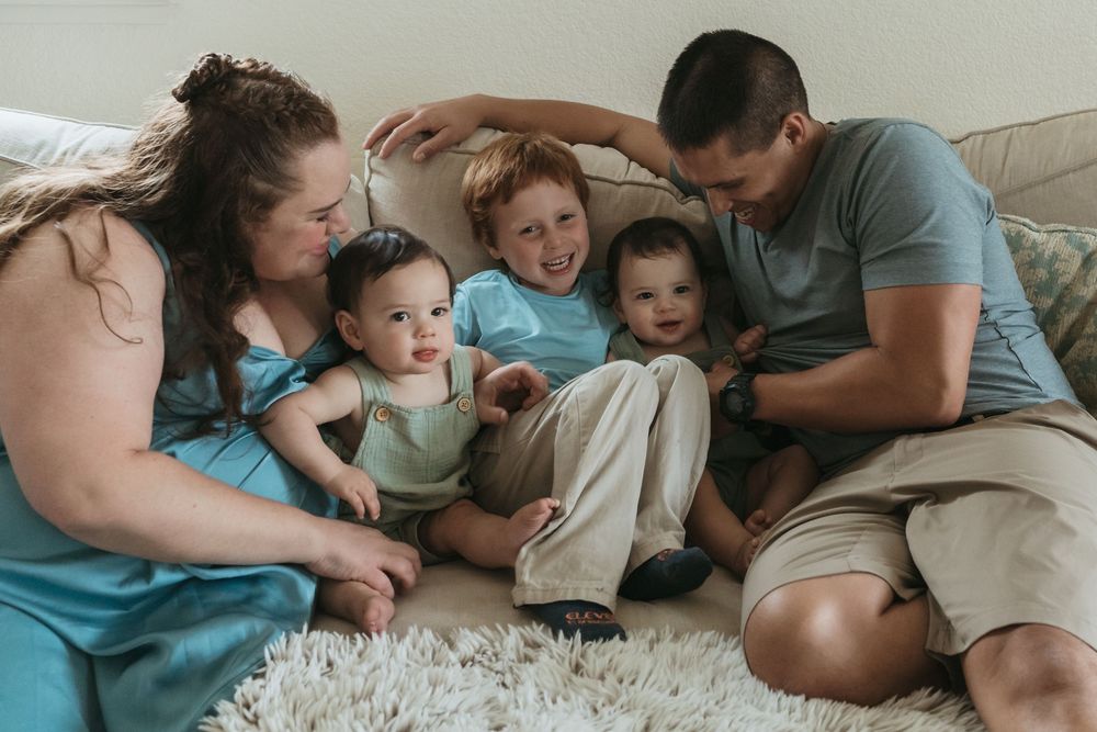 A loving family shares tender moments together while relaxing on a bed in matching blue and white outfits.