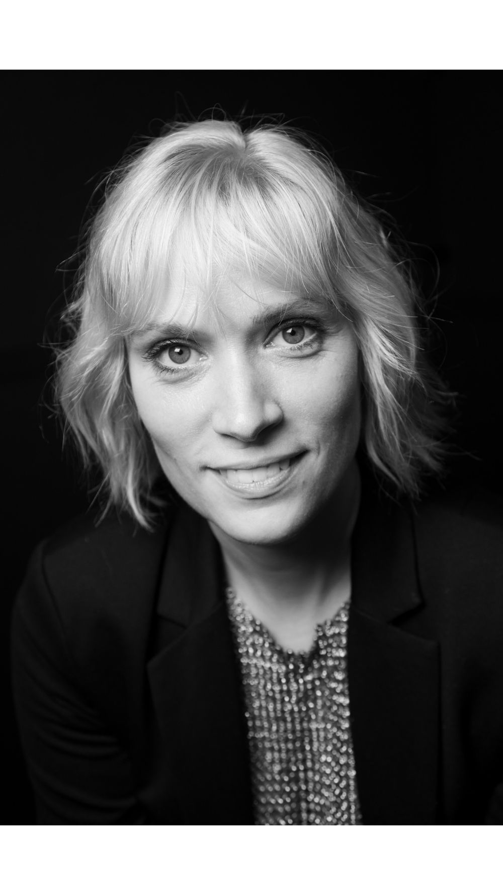 Professional closeup headshot with soft lighting featuring blonde hair and business attire.