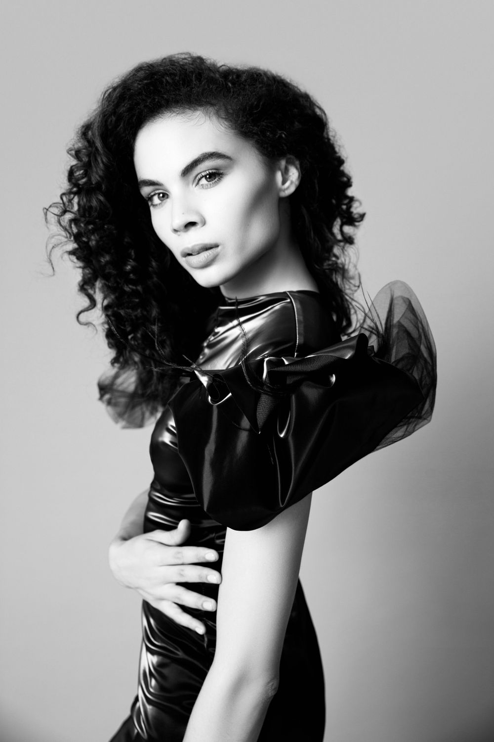 Dramatic black and white portrait featuring curly hair and ruffled fashion garment.