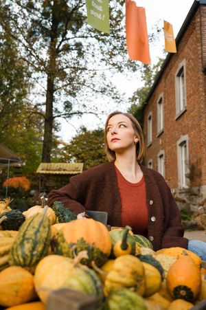 À Ohey, aux jardins de Vertumne, portrait de femme photographiée en extérieur regardant au loin parmi des citrouilles et cucurbitacées