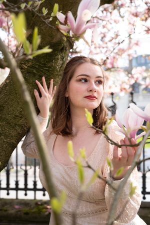 À Ciney, portrait de femme photographiée en extérieur près d’un magnolia en fleurs lors d’une séance photo printanière
