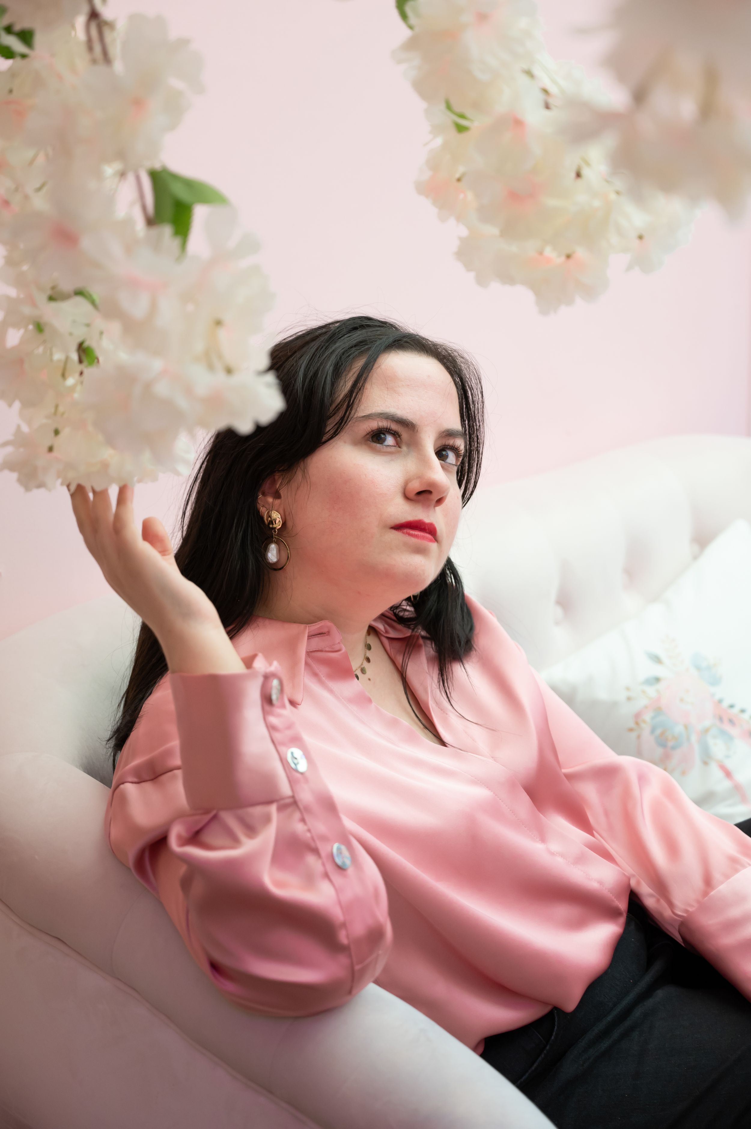 À Liège, au café Mimosa, portrait de femme photographiée en extérieur tenant une branche blanche dans un décor rose et féminin