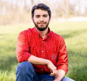 Casual outdoor portrait in red checkered shirt against natural background.