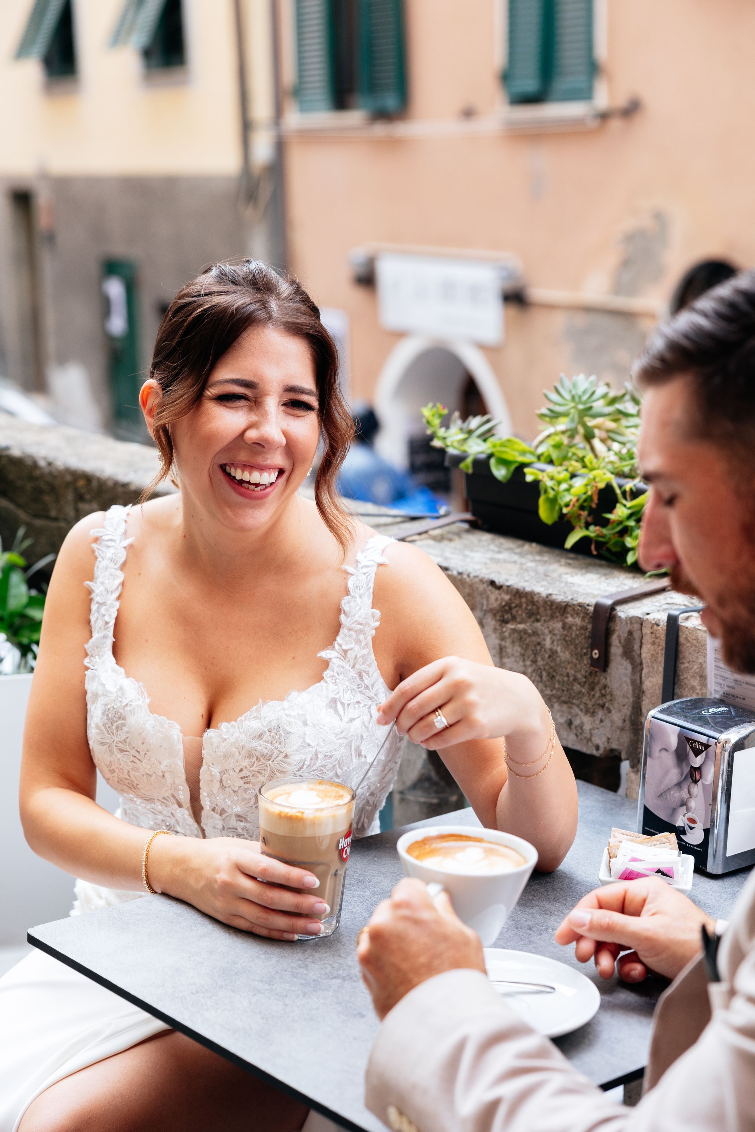 A wedding couple enjoys coffee and laughter at outdoor cafe in Cinque Terre during their relaxed and intimate elopement.